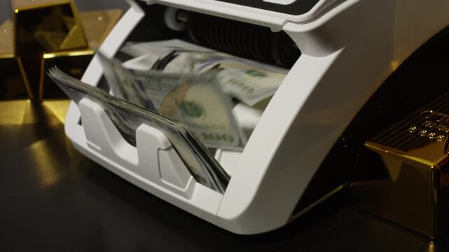 Counting hundred dollar bills with gold bars. Cash counting machine count dollars. Finance concept with money and gold. Gold and cash. Money counting process. Cash counting machine.