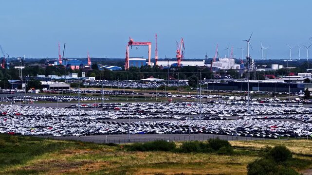 Aerial view of Volkswagenwerk Emden car manufacturing plant with rows of parked vehicles and industrial cranes in Emden, Niedersachsen, Germany.