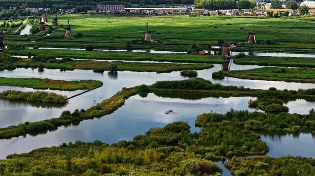 Aerial view of the historic Unesco Werelderfgoed Kinderdijk windmills surrounded by lush green fields and winding canals in Kinderdijk, Zuid-Holland, Netherlands.
