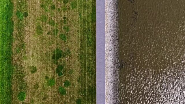Aerial view of a coastal dike separating green fields from the water in Emden, Niedersachsen, Germany.