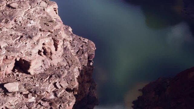 Canyon walls rise steeply above a clear body of water. The scene captures a moment of nature in a remote location during daylight. Shadows play across the rock formations.