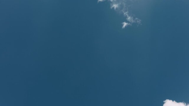 Large expanse of blue sky in the center with small clouds around the edges