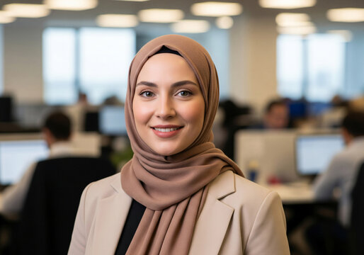 Portrait of smiling muslim businesswoman in hijab and beige jacket suit at office. Diverse positive young female leader, professional occupation, modern corporate lifestyle.