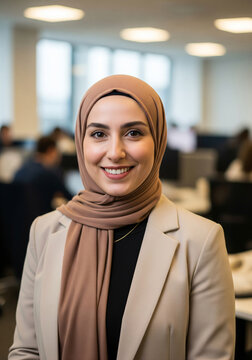 Portrait of smiling muslim businesswoman in hijab and beige jacket suit at office. Diverse positive young female leader, professional occupation, modern corporate lifestyle.