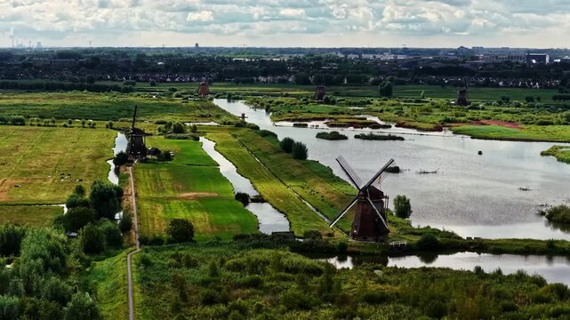 Aerial view of historic windmills at the Unesco Werelderfgoed Kinderdijk surrounded by lush green fields and winding canals in Kinderdijk, Zuid-Holland, Netherlands.