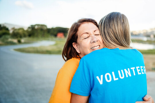 Multigenerational volunteer women hugging outdoors - Friendship, teamwork and charity support concept