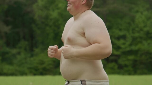 Jogging man crosses grass field. Overweight jogging shows effort. Beginner jogging fitness concept. Jogging supports healthy change.