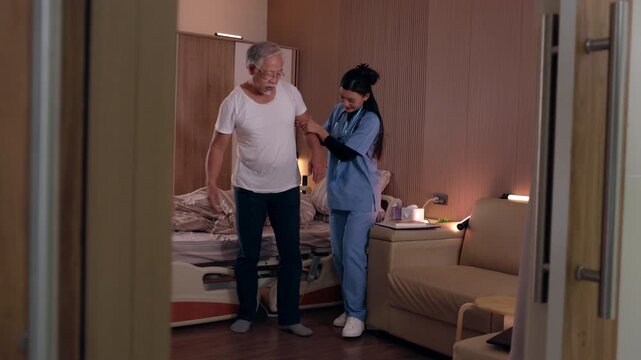 Elderly patient and female caregiver provide compassionate home health assistance, supporting senior medical care, assisted walking, bedside comfort, and daily living activity during indoor