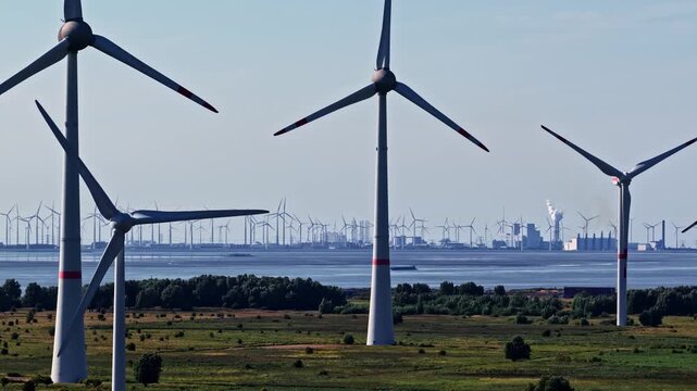 Aerial view of wind turbines in the landscape with the Volkswagenwerk Emden factory in the background near the coast in Emden, Niedersachsen, Germany.