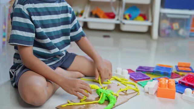 Child is playing with colorful modeling clay on the floor, shaping pieces with their hands.This activity fosters early learning, creativity