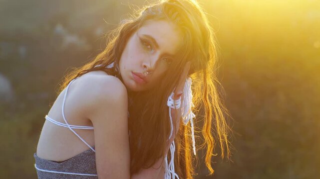 Teen models boho fashion outdoors. Bohemian girl teen poses in golden sunset light. Brunette woman wears alternative style and jewelry. Teen models summer fashion with bare shoulders.