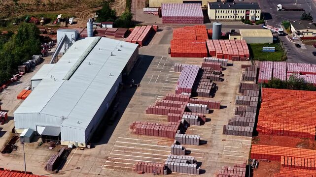 Aerial view of a brick manufacturing facility with large stacks of red bricks and a warehouse building in Konin, Wielkopolskie, Poland.