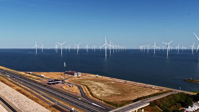 Aerial view of Windpark Fryslan, a large offshore wind farm with numerous turbines in the IJsselmeer near the highway in Breezanddijk, Friesland, Netherlands.