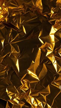 Gold foil texture background with crumpled metallic creases illuminated by warm light