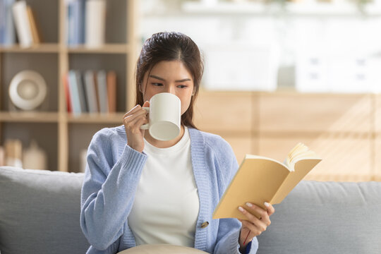 Relaxation concept, young woman drinking coffee while reading book on cozy sofa at home, enjoying peaceful leisure moment. relaxation, woman, coffee, reading, book.