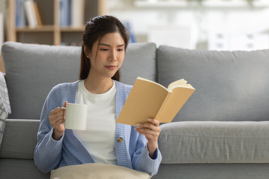 Relaxation concept, young woman drinking coffee while reading book on cozy sofa at home, enjoying peaceful leisure moment. relaxation, woman, coffee, reading, book.
