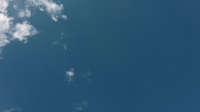 Large expanse of blue sky in the center with small clouds around the edges