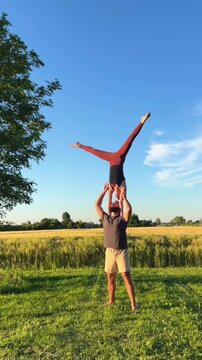 Couple Practicing Acro Yoga Outdoor Lift Balance in Sunlit Field