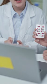 Healthcare professional presenting medication and discussing treatment options during virtual consultation using laptop in medical office.