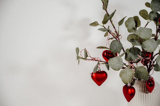 closeup eucalyptus branches decorated with red heart ornaments for christmas .Festive card with copy space