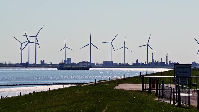 Aerial view of wind turbines and the Volkswagenwerk Emden industrial facility situated along the waterfront in Emden, Niedersachsen, Germany.