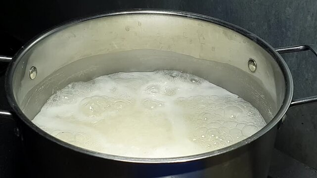 White rice boiling in a metal pot on the stove close up.