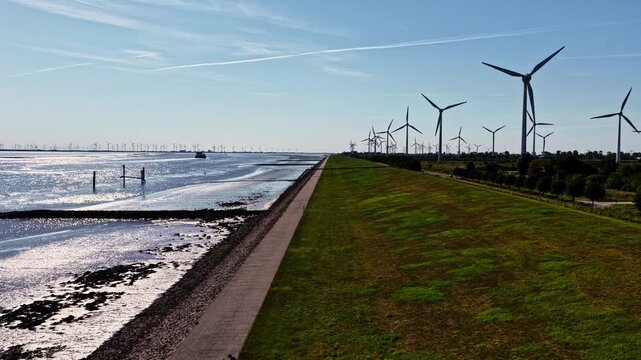 Aerial view of wind turbines along the dyke and coastline in Emden, Niedersachsen, Germany.