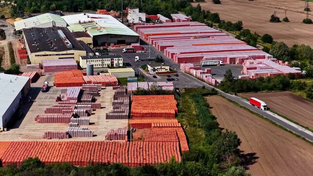 Aerial view of an industrial brick manufacturing facility with stacks of red bricks and trucks in the yard, located in Konin, Wielkopolskie, Poland.
