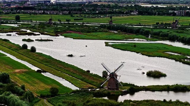 Aerial view of historic windmills at the UNESCO World Heritage site, surrounded by lush green polders and winding canals in Kinderdijk, Zuid-Holland, Netherlands.