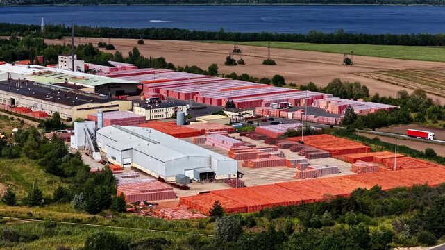 Aerial view of the industrial facility with stacks of red bricks near the lake in Konin, Wielkopolskie, Poland.