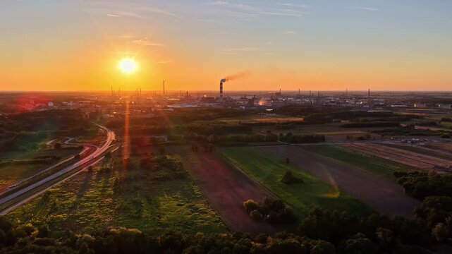 Aerial view of the Orlen Plock Production Plant with industrial chimneys and smoke plumes under a golden sunset sky in Plock, Wojewodztwo mazowieckie, Poland.