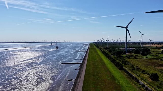 Aerial view of wind turbines along the Ems river with green fields and a waterway in Emden, Niedersachsen, Germany.