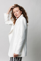 Obraz na płótnie Canvas Middleaged woman with natural skin wears a white blazer, posed in a studio, looking at the camera with calm confidence and poise for editorial use.