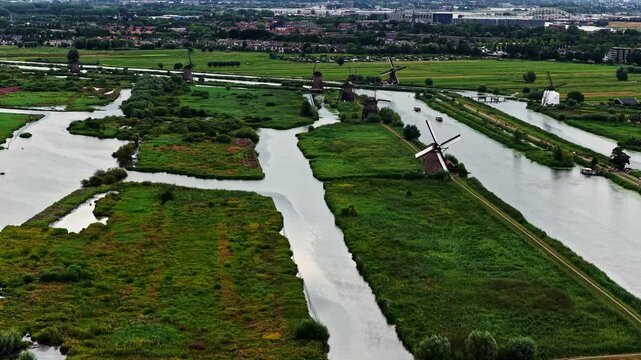 Aerial view of historic windmills at Unesco Werelderfgoed Kinderdijk surrounded by lush green polders and winding canals in Kinderdijk, Zuid-Holland, Netherlands.