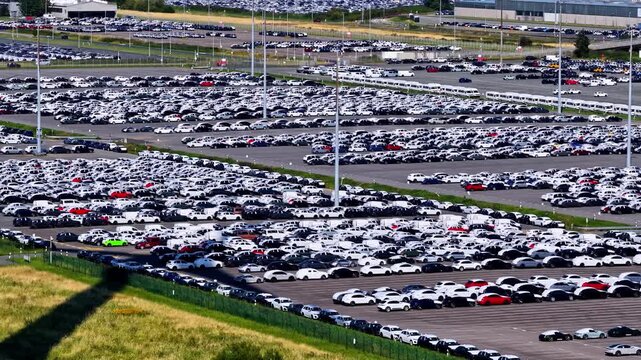 Aerial view of the extensive car storage lot at the Volkswagenwerk Emden factory with thousands of new vehicles parked in rows in Emden, Niedersachsen, Germany.
