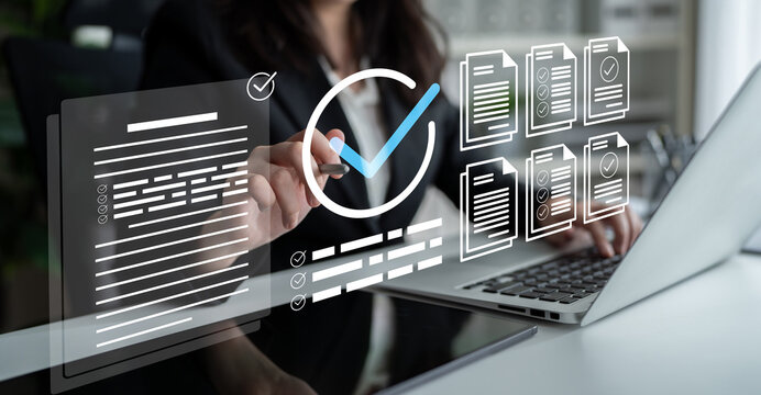 A professional woman interacts with a laptop, utilizing digital graphics to manage documents and streamline processes in a modern office, highlighting productivity and technology. Ledger