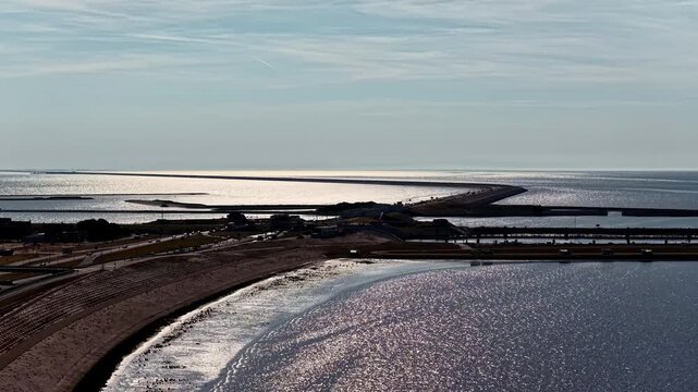Aerial view of the Windpark Fryslan wind farm and the Afsluitdijk causeway stretching across the water in Breezanddijk, Friesland, Netherlands.
