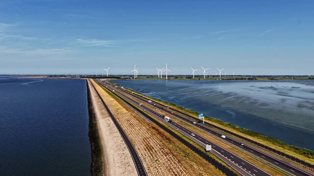 Aerial view of Windpark Fryslan wind turbines along the Afsluitdijk highway with traffic and water in Breezanddijk, Friesland, Netherlands.