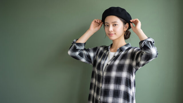 黒いベレー帽とチェック柄のシャツを着て微笑む若い女性