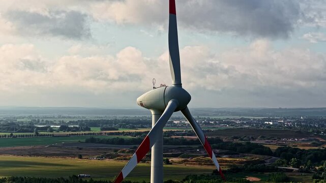 Aerial view of a large wind turbine with red-tipped blades overlooking the industrial landscape of PCK Raffinerie GmbH in SchwedtOder, Brandenburg, Germany.