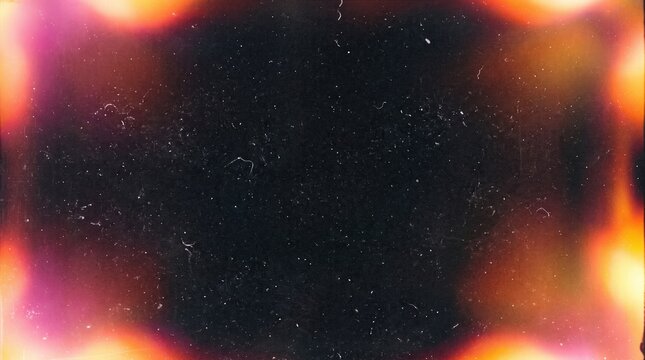 Vintage film texture showing vibrant orange and pink light leaks around a dark grainy frame. Film texture adds a nostalgic analog aesthetic with dust and scratch details for cinematic overlay.