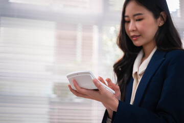 Obraz premium Asian businesswoman using smartphone for financial advisor wealth planning during professional office work