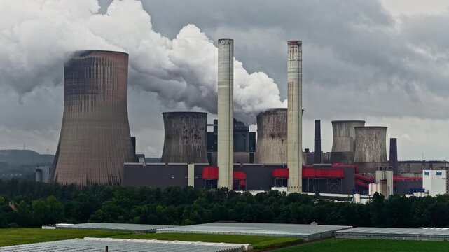 Aerial view of RWE Power AG power plant Niederaussem with cooling towers emitting steam over industrial facilities in Bergheim, Nordrhein-Westfalen, Germany.