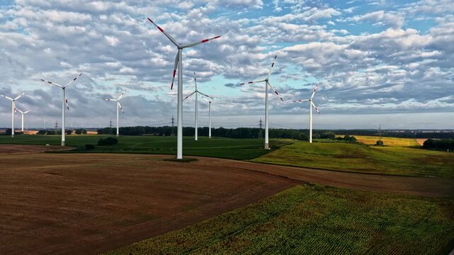 Aerial view of wind turbines standing in a vast agricultural field under a cloudy sky in Schwedt oder, Brandenburg, Germany.