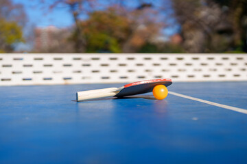Ping pong paddle and ball on outdoor table © Uriel Lu Photo