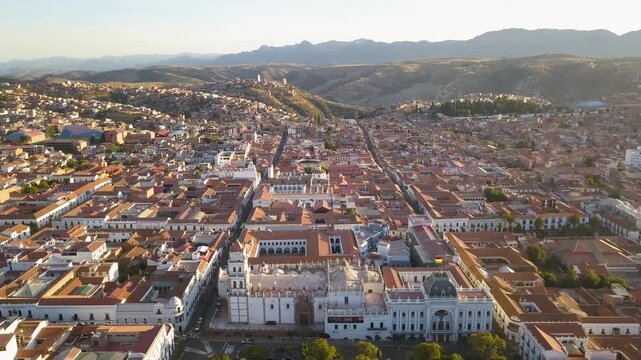 Aerial view of Sucre city in Bolivia featuring colonial architecture and red tile roofs during sunset.