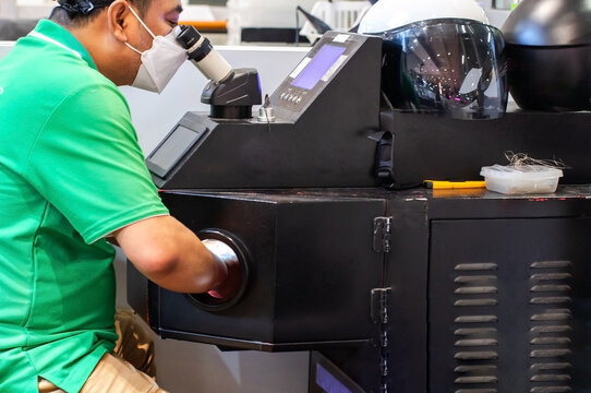 Technician Operating Laser Welding Machine with Stereo Microscope for Jewelry Repair