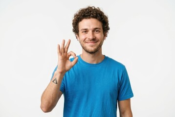 Fototapeta premium Cheerful Young Man with Curly Hair Showing OK Sign Gesture for Approval Isolated on White Background