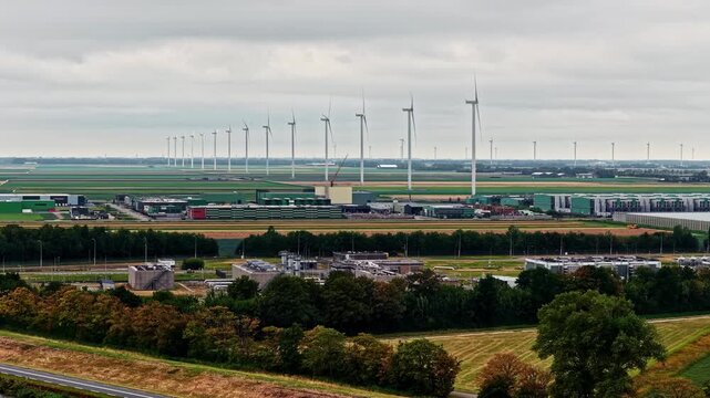 Aerial view of the Agriport A7 wind farm with rows of wind turbines and industrial facilities surrounded by agricultural fields in Middenmeer, Noord-Holland, Netherlands.