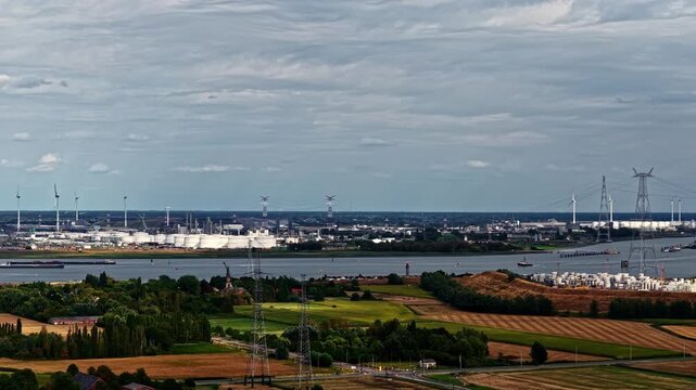 Aerial view of Doel Nuclear Power Plant along the Scheldt river, with cooling towers, industrial cranes, and fields in Beveren-Kruibeke-Zwijndrecht, Vlaanderen, Belgium.